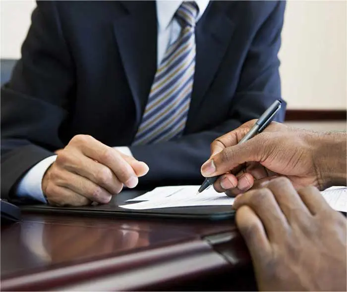 A man in a suit is writing on paper